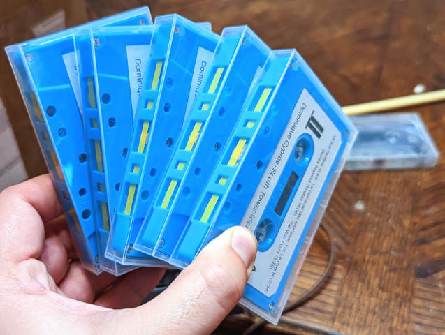 A stack of identical aqua-colored DIY demo cassettes for the album South Tower by Dominique Cyprès, in clear poly boxes