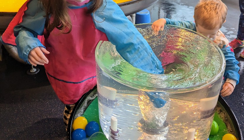 Children dipping their hands into a whirlpool generator